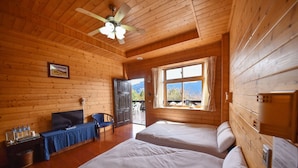 Habitación de cabaña de madera con dos camas, un televisor, un escritorio con silla y una ventana con vista a la montaña.