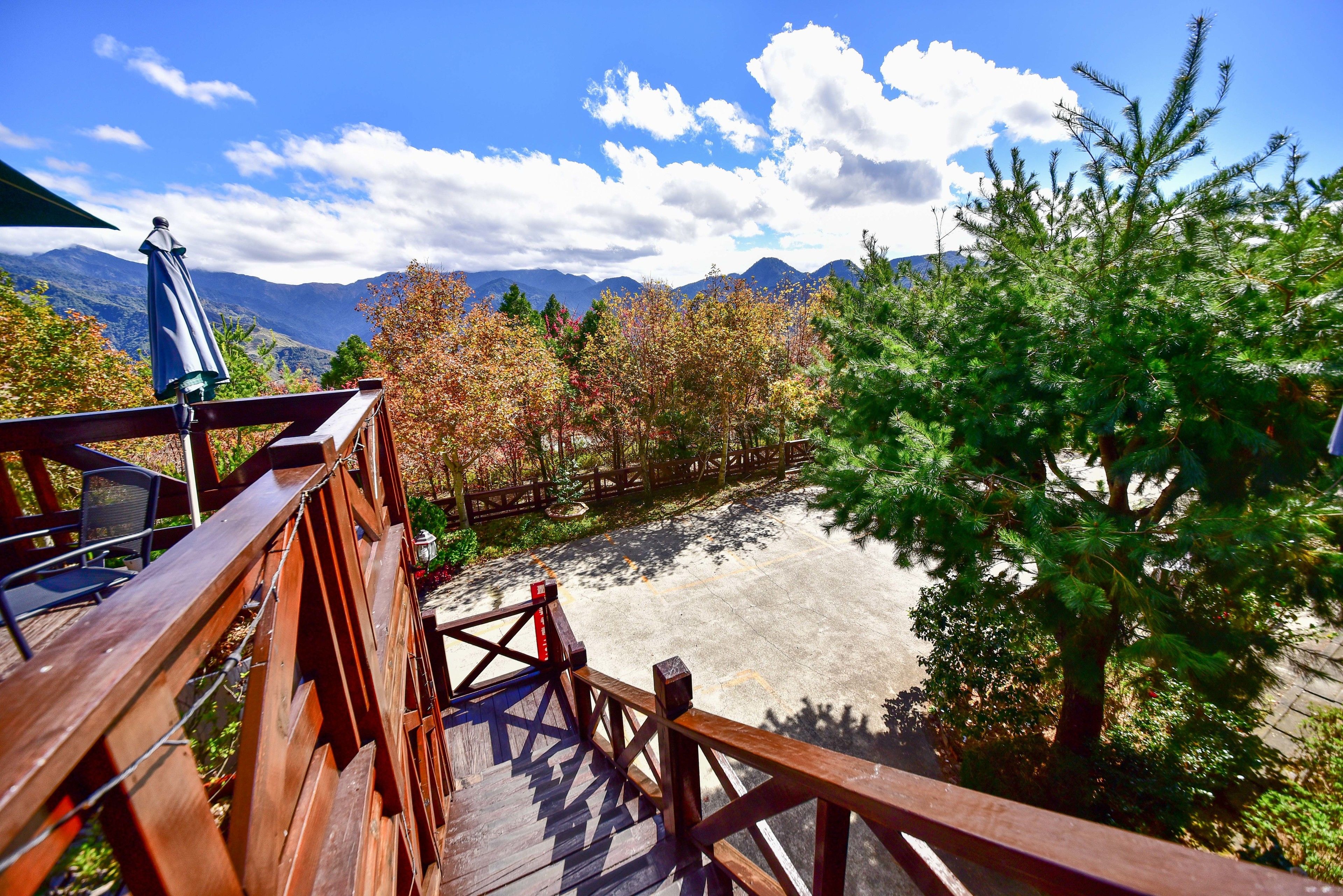 Una terraza de madera con vistas a un paisaje montañoso y follaje otoñal.