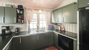 A compact kitchen with dark cabinets, a coffee maker, a toaster, and a refrigerator. - Amazing home in Kvam with kitchen (Kvam)
