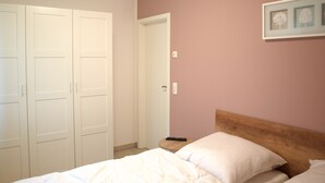 A bedroom with a bed, a nightstand, a wooden headboard, a closet, and a door.