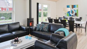 A modern living room with a black leather sofa, a coffee table with candles, and a wood-burning stove. - Awesome home in Aabenraa with sauna (Aabenraa)