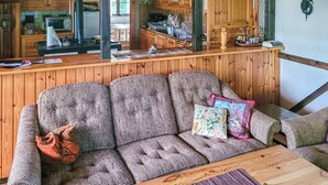 Un interior de madera con un sofá, una mesita de centro y una zona de cocina al fondo.