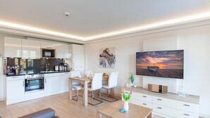 A modern apartment with a kitchen, dining area, living room, and a large TV. - 1 bedroom lovely apartment in Binz (Prora/Rügen)