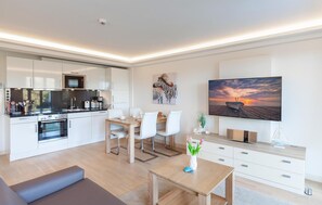 A modern apartment with a kitchen, dining area, living room, and a large TV. - 1 bedroom lovely apartment in Binz (Prora/Rügen)