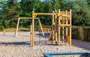 A playground with wooden structures and a sandy ground.