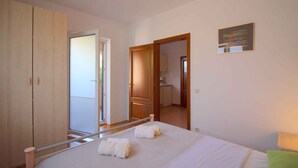 A bedroom with a bed, a wardrobe, a door leading to a bathroom, and a painting on the wall. - Holiday apartment with terrace (Poreč)
