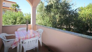 An outdoor balcony with a table and chairs, a view of trees and a building in the background. - Holiday apartment with terrace (Poreč)