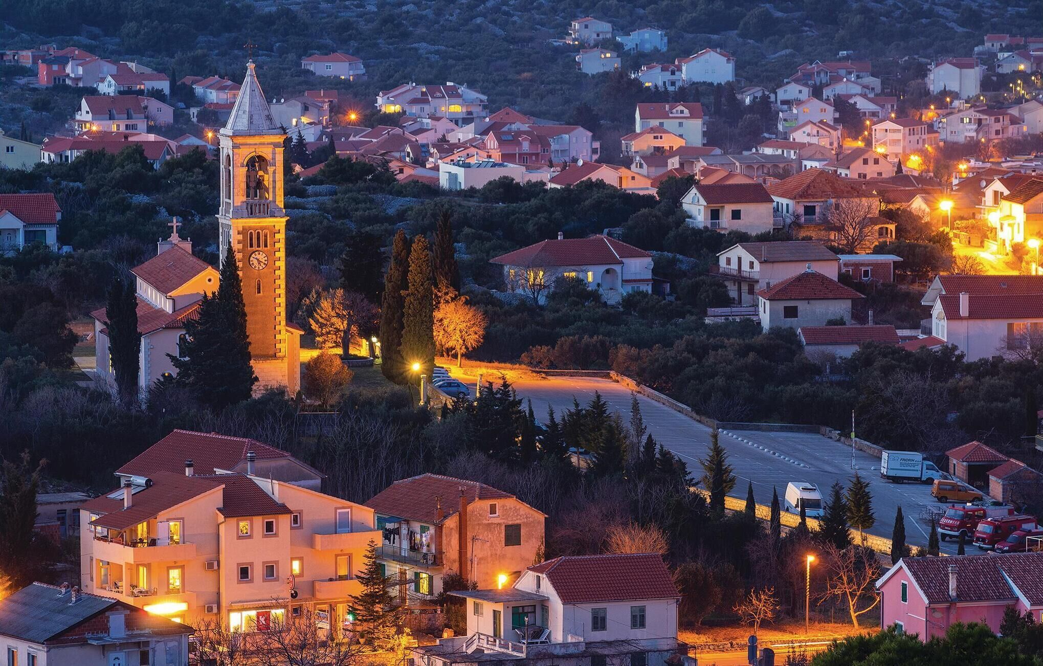 A town with a prominent clock tower, surrounded by residential buildings and a main road.