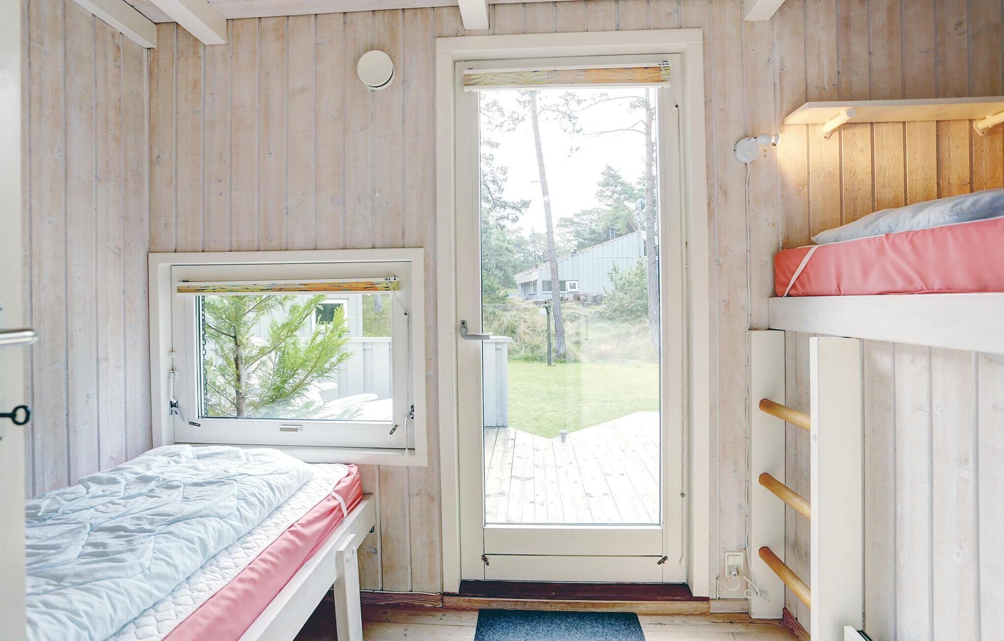 Una cabaña pequeña de una sola habitación con interior de madera, una ventana, una puerta y una cama doble.