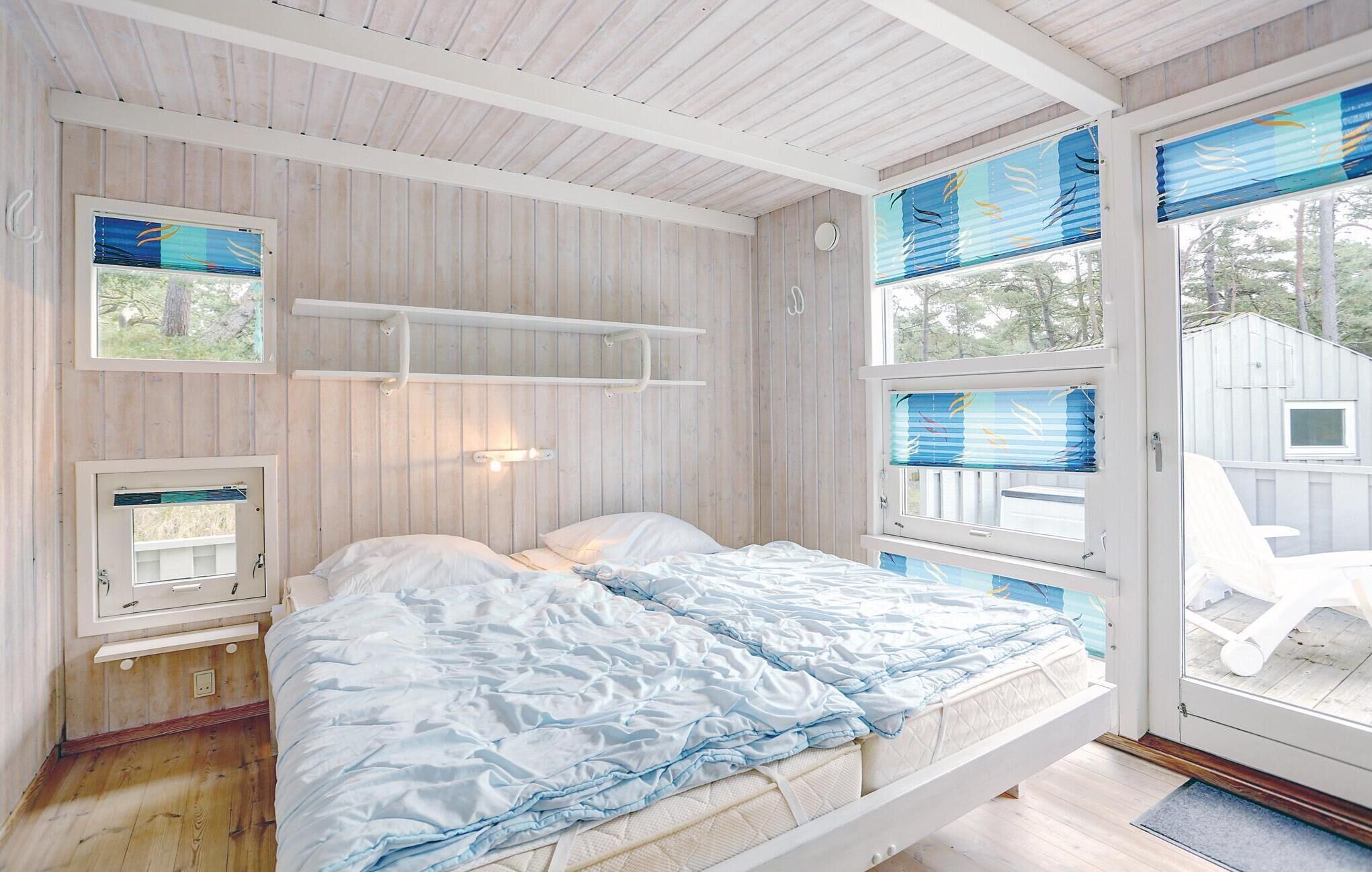 A bedroom with a bed, a window with blinds, and a door leading to an outdoor area.