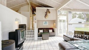 A spacious living area with a large television, a sofa, a glass coffee table, and a zebra head sculpture. - Stunning home in Nexø with kitchen (Nexø)