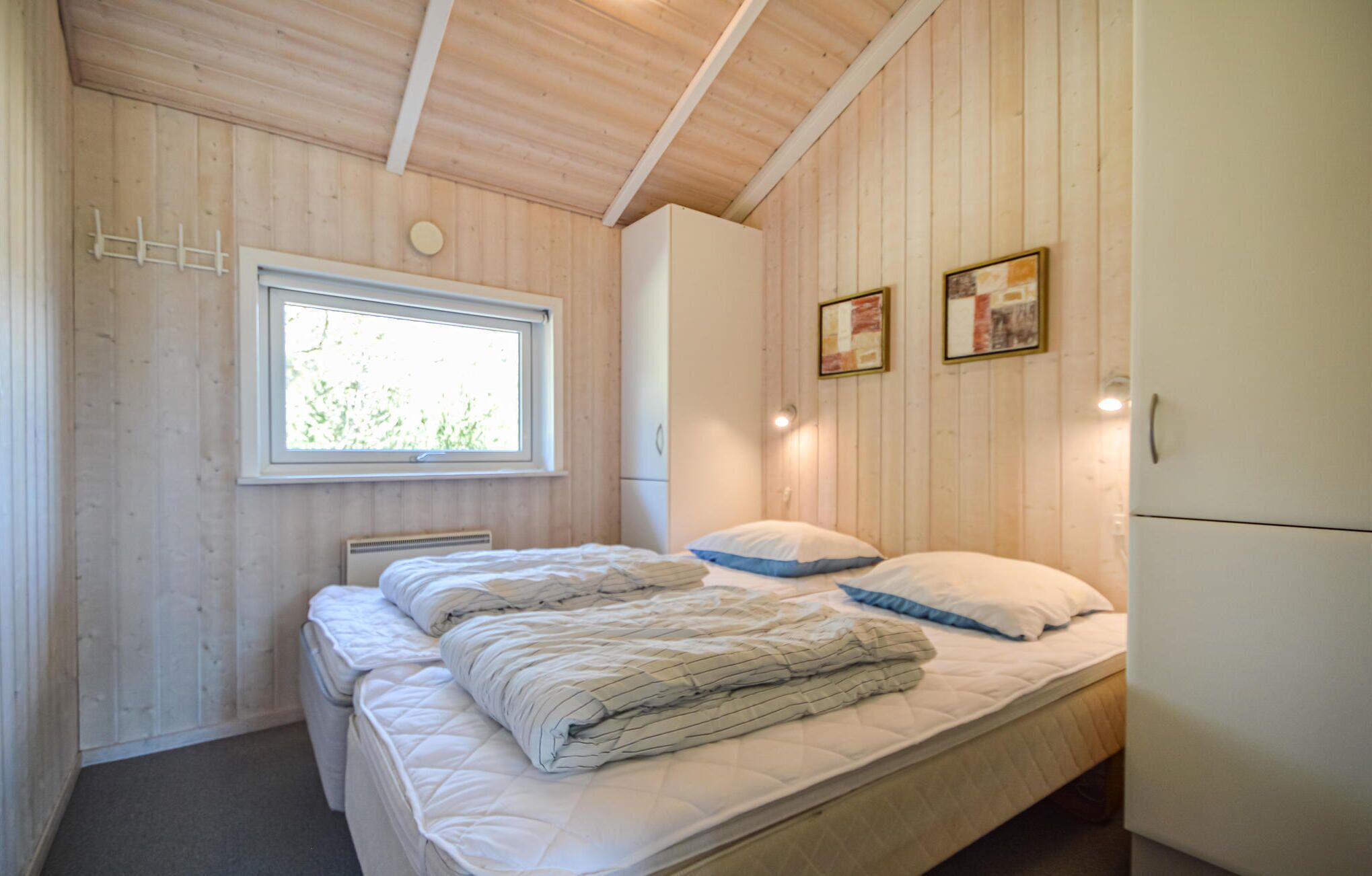 Une chambre à coucher avec un lit, une fenêtre, un radiateur fixé au mur et une armoire blanche.