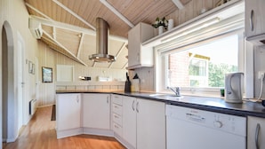 Una cocina moderna con armarios blancos, un lavavajillas Bosch y un ventanal que proporciona luz natural.