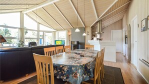 Una habitación acogedora y bien iluminada, con techo de madera, una mesa de comedor con mantel floral y un sofá.