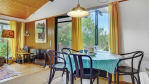 A dining area with a round table, chairs, and a view of greenery outside. - 3 bedroom beautiful home in Idestrup (Idestrup)