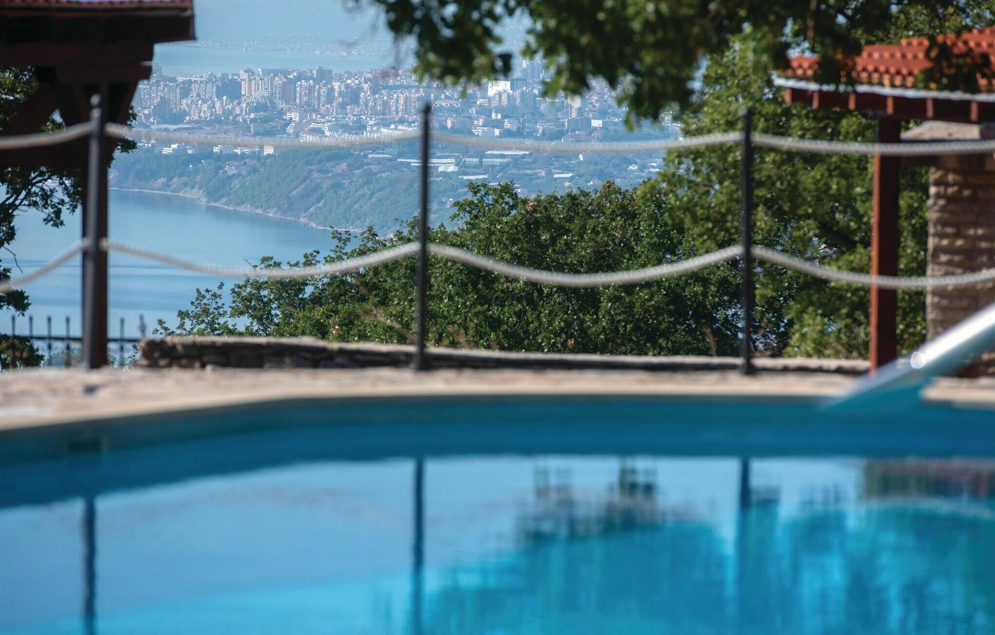 En swimmingpool med utsikt över stadssiluetten och grönområden.
