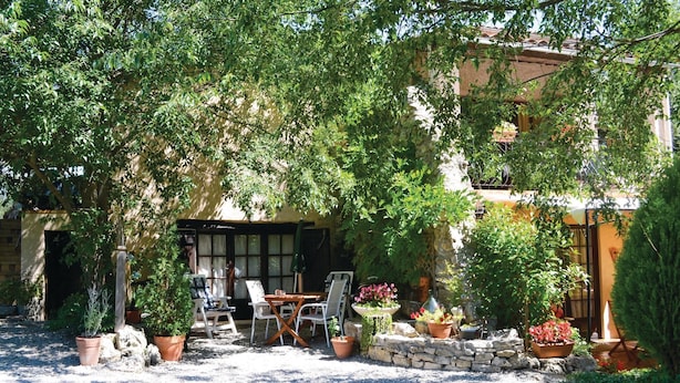 An outdoor seating area with a table and chairs, surrounded by potted plants and a stone wall. - 1 bedroom amazing apartment in Lorgues (Lorgues)