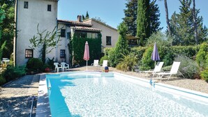 A swimming pool with lounge chairs and umbrellas, surrounded by a garden and a building with a tiled roof. - 1 bedroom amazing apartment in Lorgues (Lorgues)