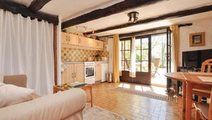 A cozy living room with a sofa, a dining table, and a kitchen area with wooden cabinets and a tiled backsplash. - 1 bedroom amazing apartment in Lorgues (Lorgues)