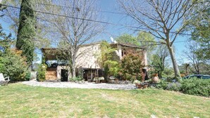 A rustic house with a stone facade, a wooden deck, and a garden with various plants and a small pond. - 1 bedroom amazing apartment in Lorgues (Lorgues)