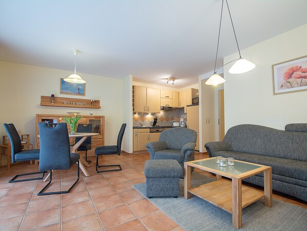 Un salon moderne comprenant un canapé, des fauteuils, une table basse et un coin repas avec une table et des chaises.