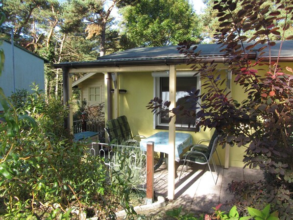 A small house with a porch, a table, and chairs.