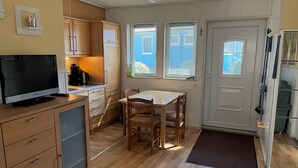 Een kleine keuken met houten kastjes, een eettafel en een televisie.