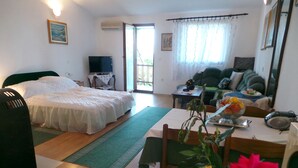 Een ruime woonkamer met een groot bed, een bank, een eettafel en een televisie.