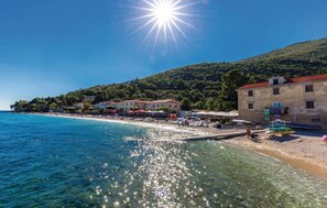 A coastal town with clear blue waters, a sandy beach, and buildings with red roofs. - Awesome home in Moscenicka draga (Moscenicka draga)