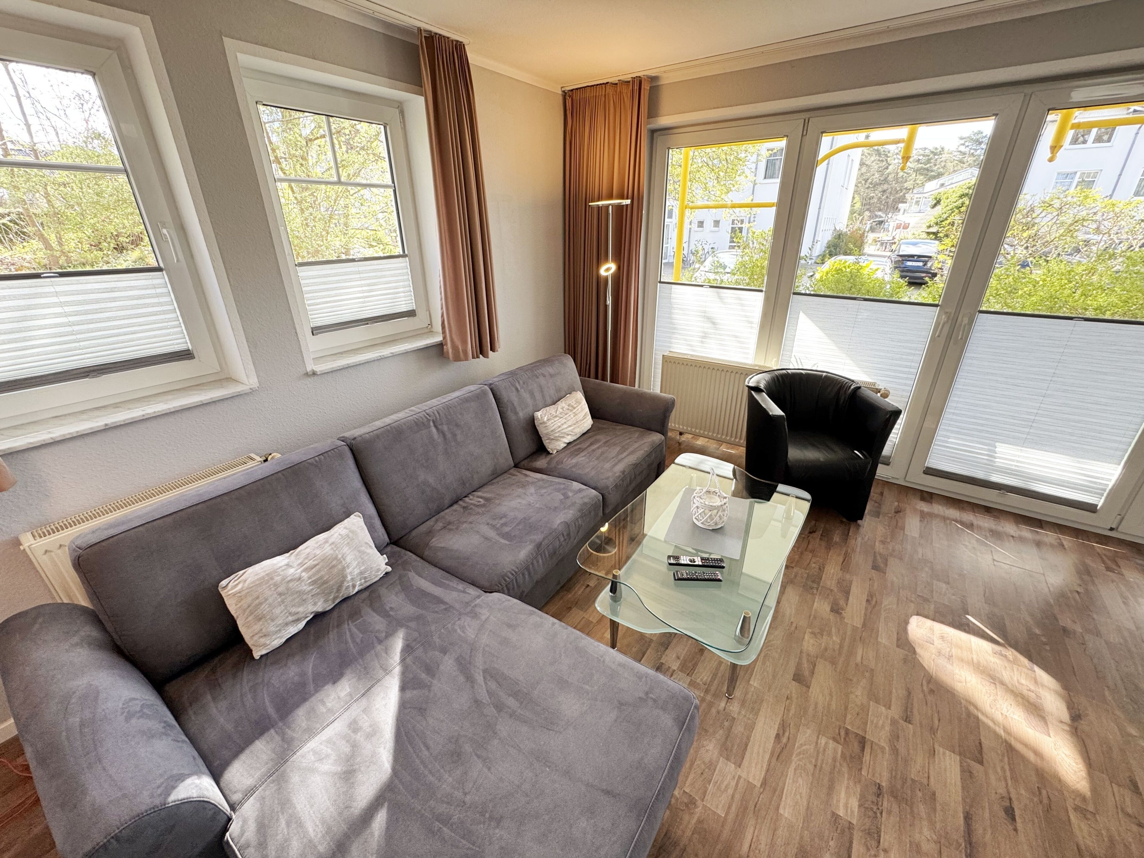 A modern living room with a grey sectional sofa, a glass coffee table, and a black armchair.