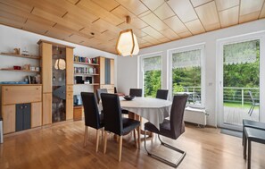Een eethoek met een ronde tafel, zwarte stoelen en een houten plafond.