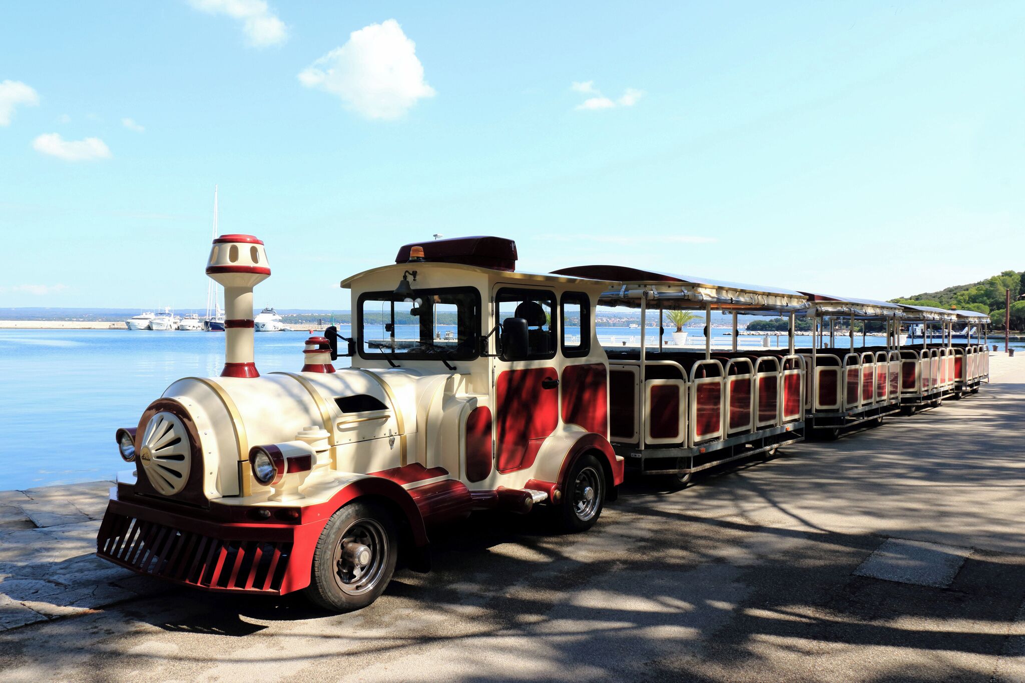 A vintage train with a red and white color scheme parked by the water.