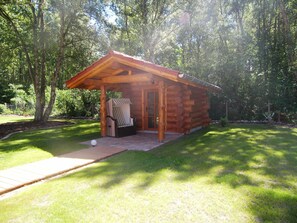 Une cabane en rondins dotée d’un porche et d’un espace salon abrité.