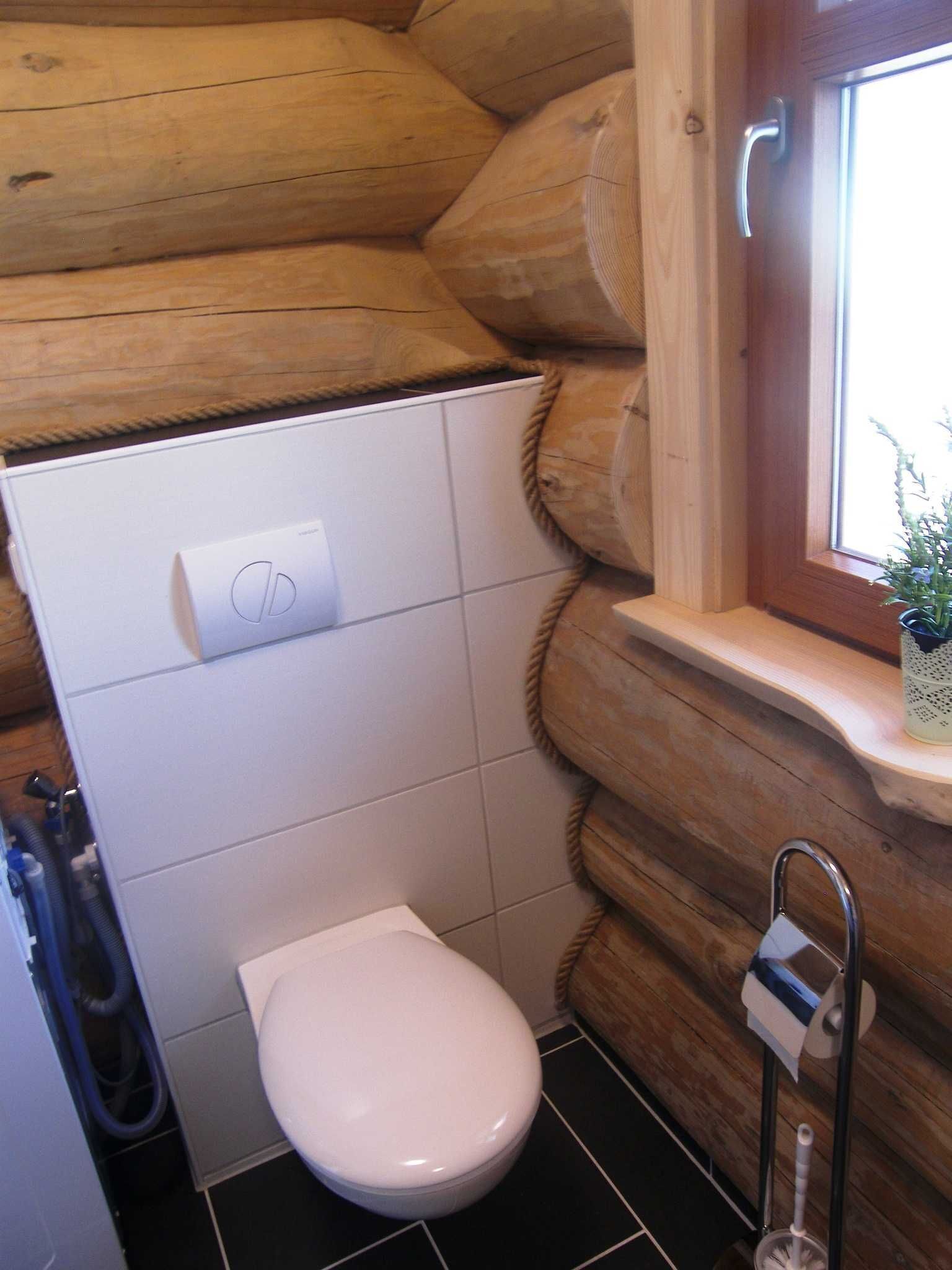 Une petite salle de bain comprenant des toilettes, un sèche-mains et une fenêtre avec une plante.