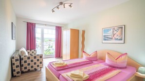 Una camera da letto con un letto, due sedie, un armadio e una finestra con tende.