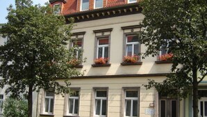 Un immeuble à plusieurs étages, de style architectural classique, caractérisé par un toit plat et des fenêtres disposées de manière symétrique.