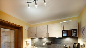 A kitchen with wooden cabinets, a stainless steel sink, a coffee maker, and a microwave. - Apartment 2 - Vacation Lohbinder (Fam. Holzer) (Rottach-Egern)