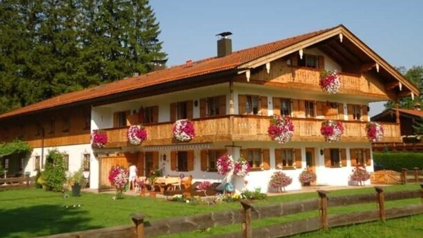 A two-story building with balconies, a wooden facade, and flower arrangements. - Apartment 2 - Vacation Lohbinder (Fam. Holzer) (Rottach-Egern)