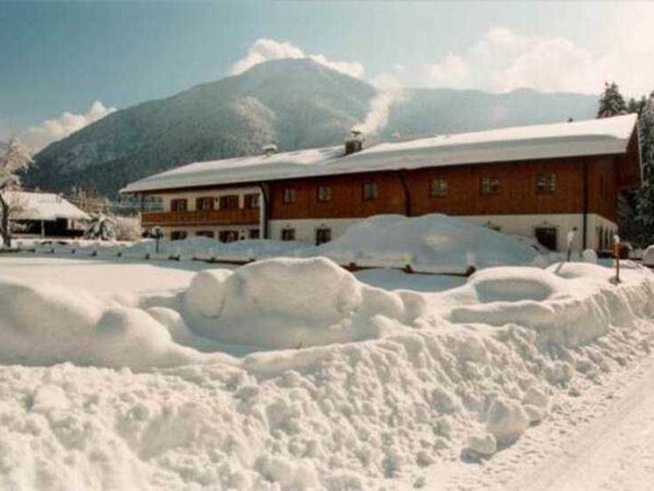 Un edificio con tejado nevado y montañas al fondo.