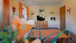 A living room with a television, wooden cabinet, and a small shelf. - Apartment 2 - Vacation Lohbinder (Fam. Holzer) (Rottach-Egern)