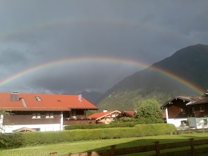 A house with a red roof, surrounded by greenery and mountains in the background. - Apartment 2 - Vacation Lohbinder (Fam. Holzer) (Rottach-Egern)