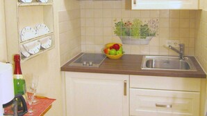 Una cocina pequeña con gabinetes blancos, un lavamanos, una encimera y un frutero.