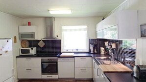 Uma cozinha moderna com armários brancos, forno embutido, micro-ondas, lava-louças e uma janela grande que proporciona luz natural.