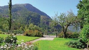 Um jardim com um caminho de pedra, vegetação exuberante e uma montanha ao fundo.