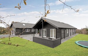 A two-story wooden house with a sloped roof, a porch, and a small trampoline in the yard. - Beautiful home in Ebeltoft with sauna (Ebeltoft)