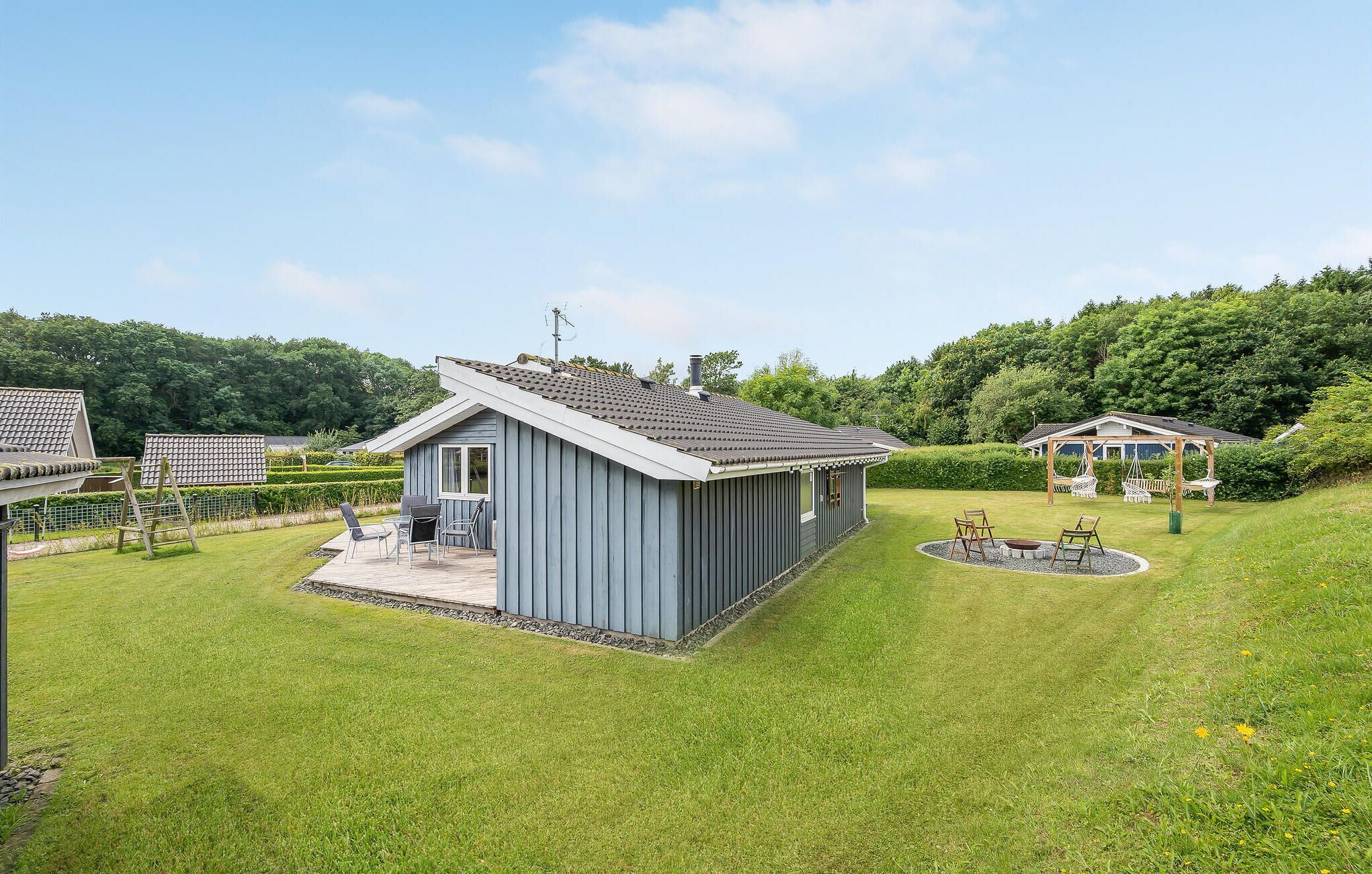 A small, single-story building with a sloped roof, surrounded by well-maintained grass and a circular garden feature.