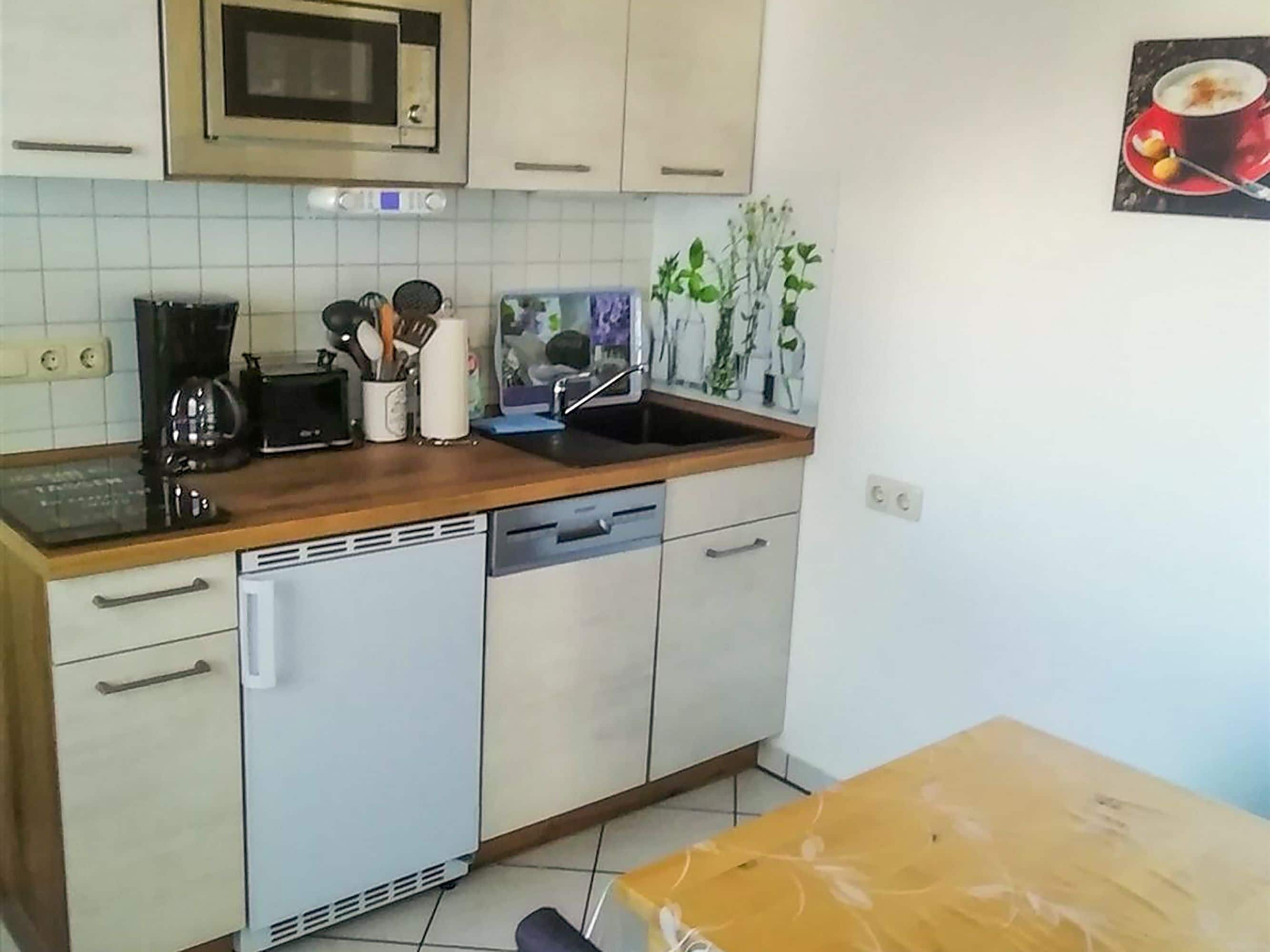 Eine Küche mit Mikrowelle, Toaster, Spüle und verschiedenen Küchenutensilien.