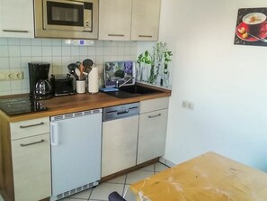 A kitchen with a microwave, toaster, sink, and various utensils.
