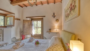 Une chambre confortable avec un lit, une table de chevet, une lampe, une fenêtre et un miroir.