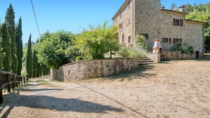 Un bâtiment en pierre, à l’aspect rustique, avec une allée en gravier et un mur de pierres.